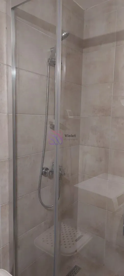 Tuš kabina sa staklenim paravanom u popločanom kupatilu.