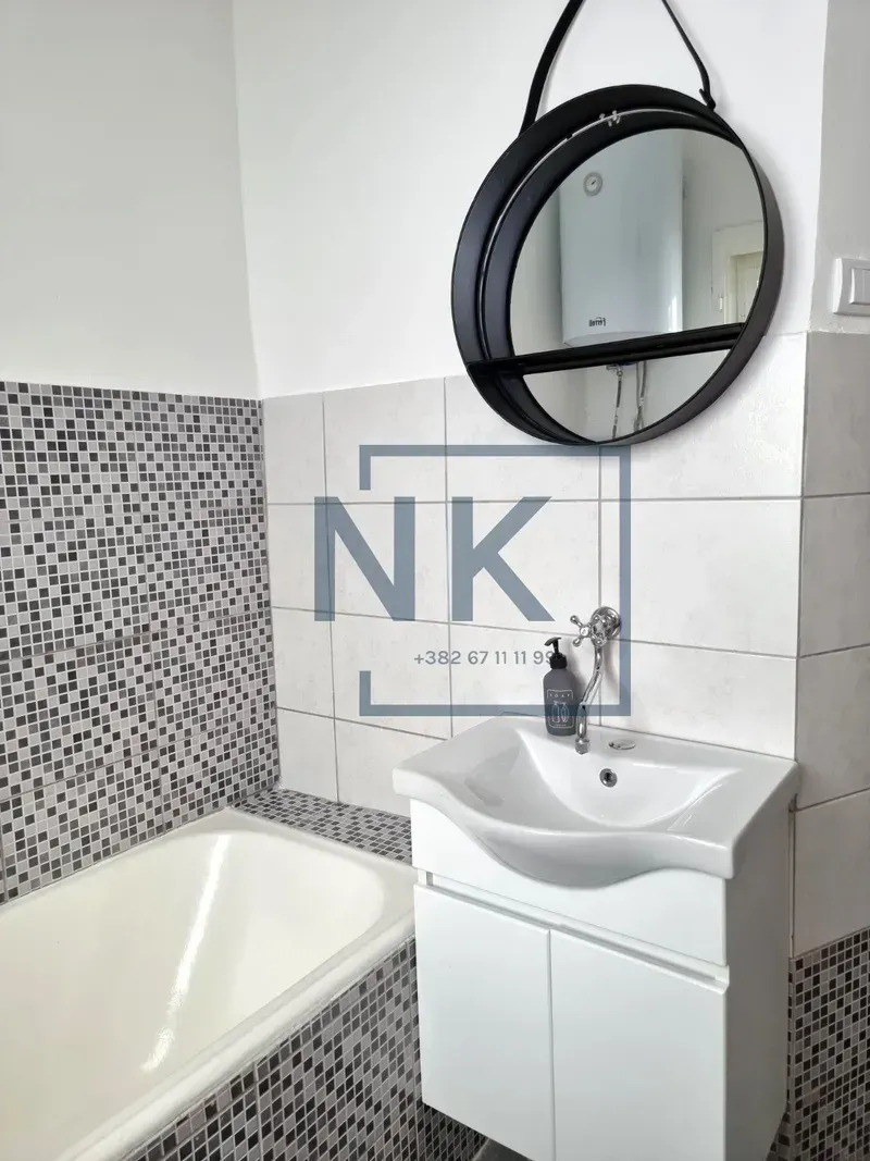 Bathroom with a vanity, cabinet, mirror, and bathtub.
