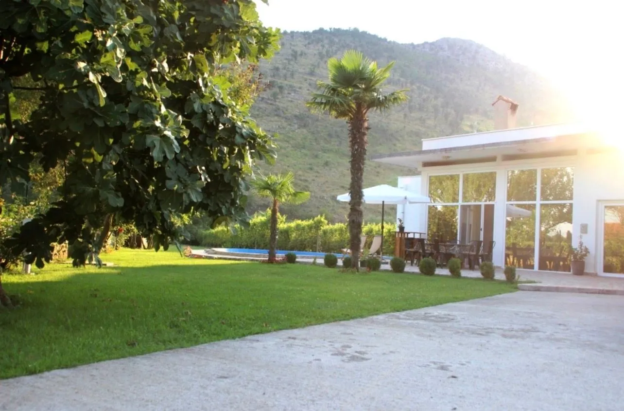 Exterior of the house with a landscaped yard, swimming pool, and hill view.