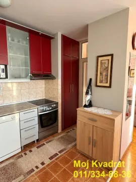 Small kitchen with red cabinets and a stove. - image 8