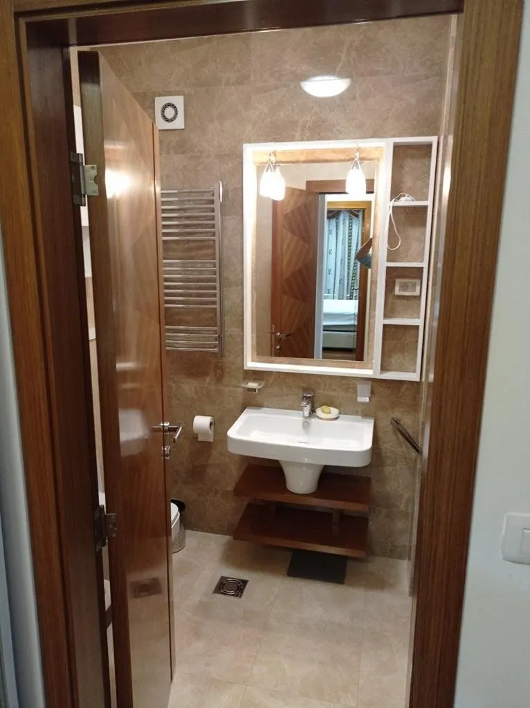 View from the hallway into a furnished bathroom with a washbasin and a mirror.