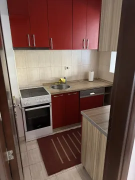 Mala kuhinja sa crvenim elementima, šporetom i sudoperom. - image 5