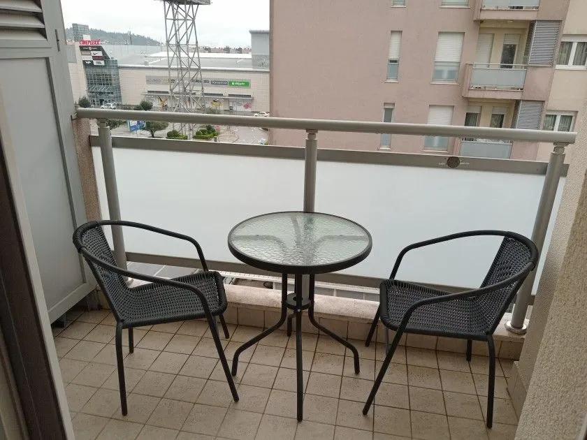 Manji namješteni balkon sa staklenim stočićem i dvije stolice.