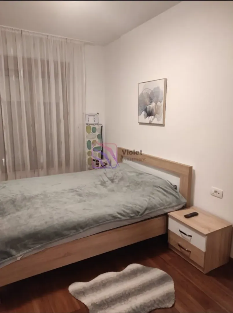 Bedroom with a double bed, nightstand, and a window with curtains.