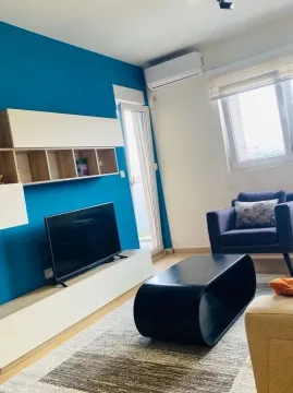 Living room with a blue accent wall, TV, and seating furniture. - image 3