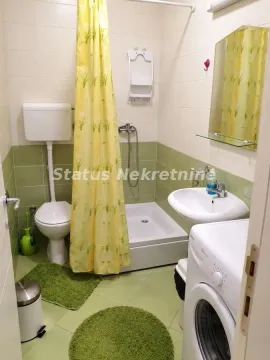 Smaller bathroom with a shower cabin, washbasin, toilet, and washing machine. - image 3