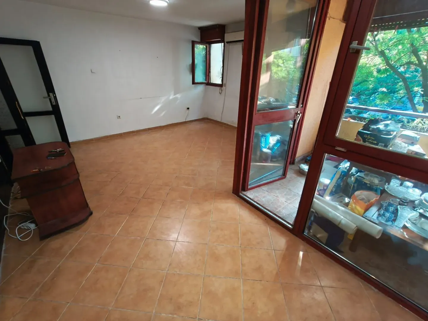 Prazna prostorija sa keramičkim pločicama i izlazom na terasu.