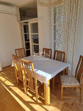 Trpezarija sa drvenim stolom i stolicama pored prozora sa zavesama. - image 17