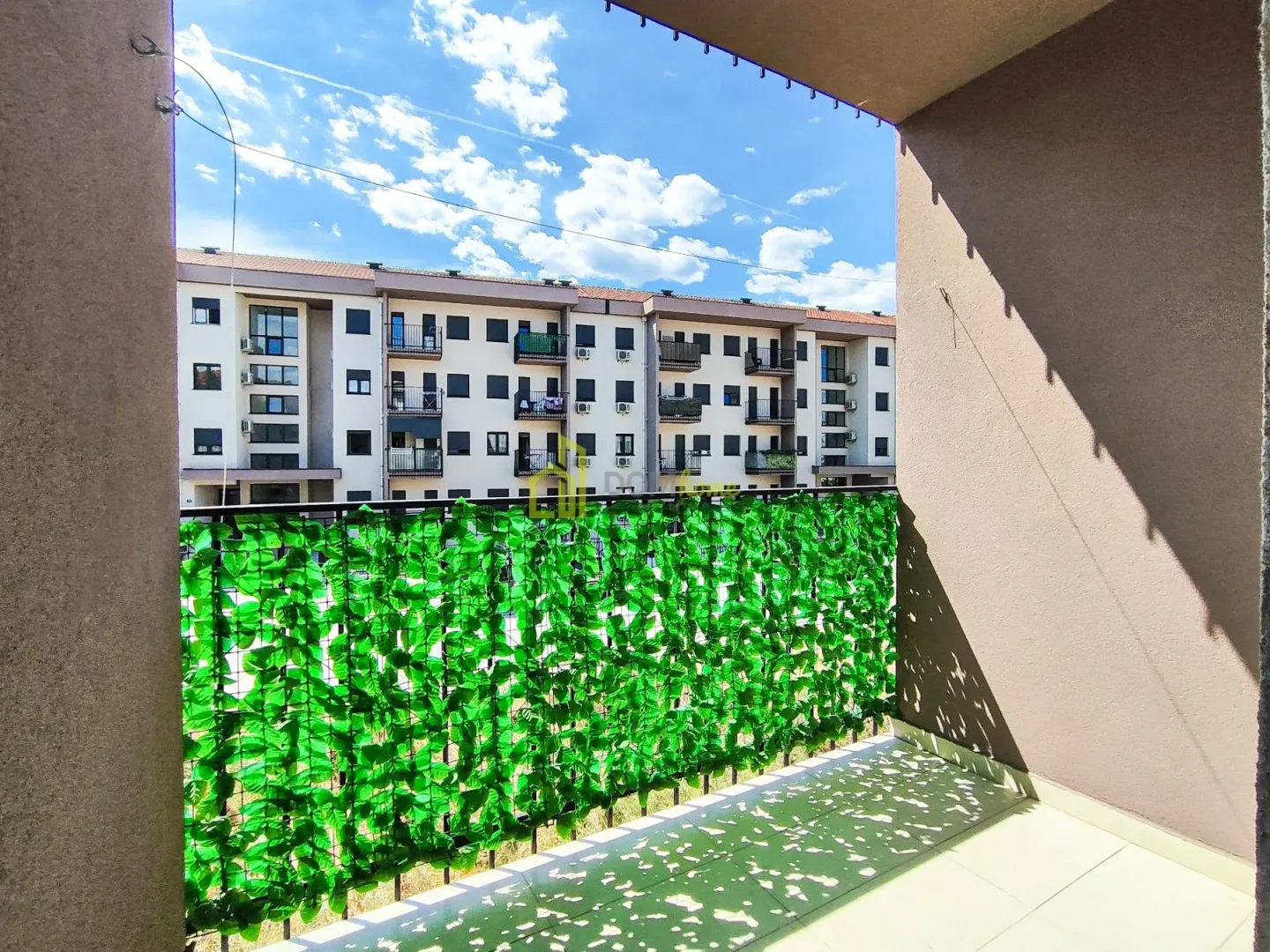 View from the balcony overlooking surrounding buildings and the blue sky.