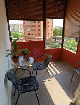 Natkriveni balkon sa garniturom za sjedenje i pogledom na okolne zgrade. - image 3