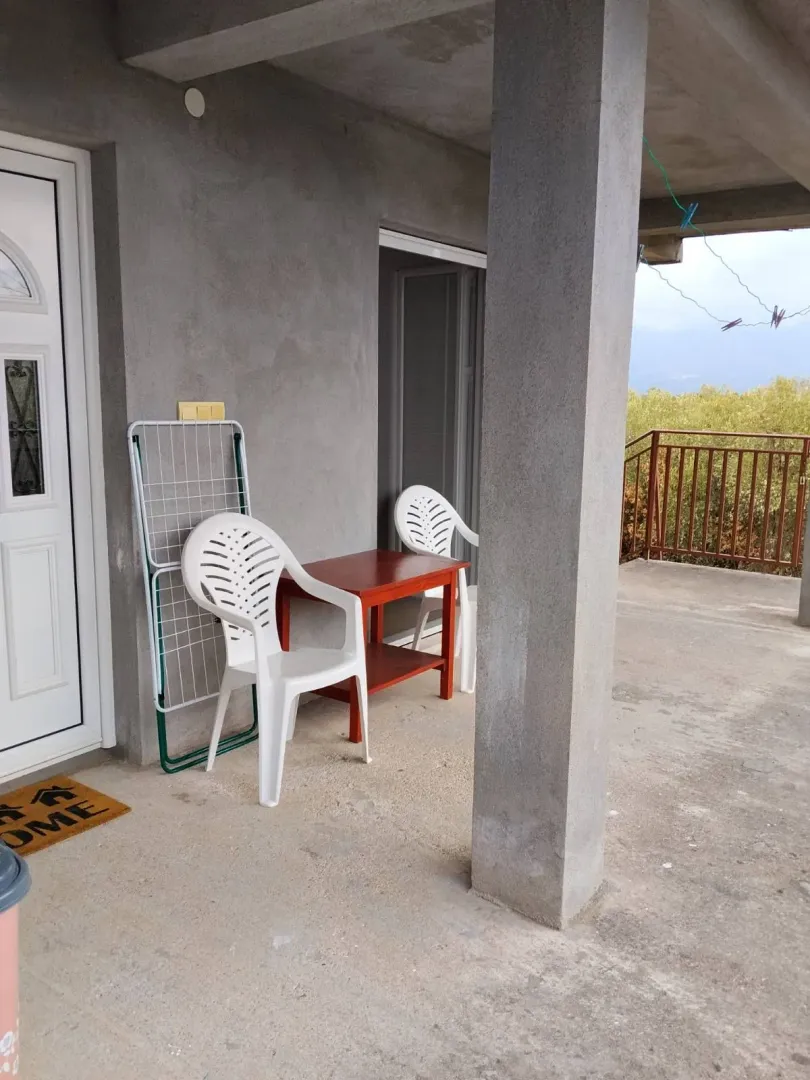 Covered terrace in front of the entrance with a table, chairs, and a clothes drying rack.
