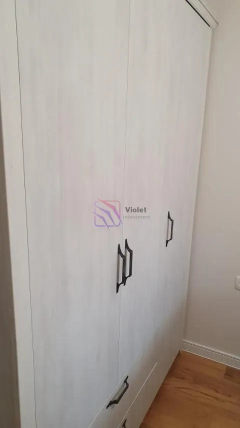 Prikaz bijelog ormara sa tamnim ručkama u enterijeru.