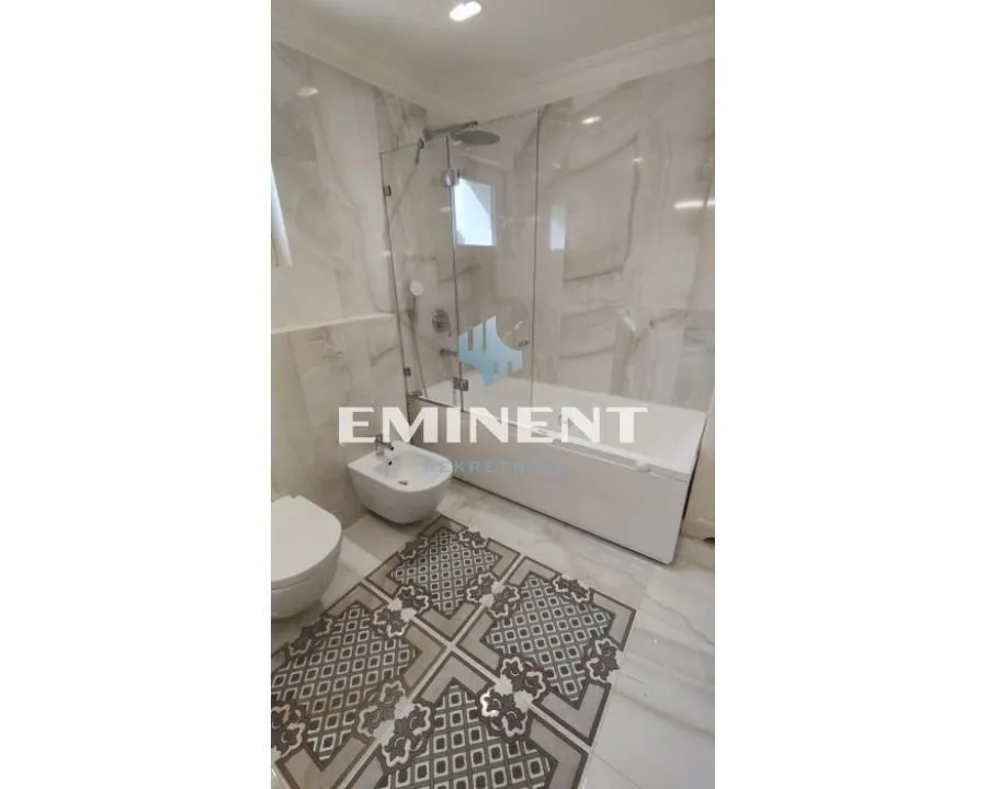 Modernly equipped bathroom with a bathtub, glass shower screen, and sanitary fixtures.