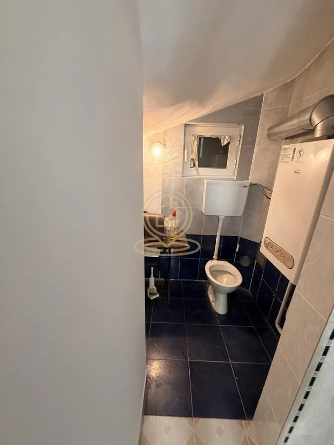 Small bathroom with tiles, toilet, and wall-mounted boiler.
