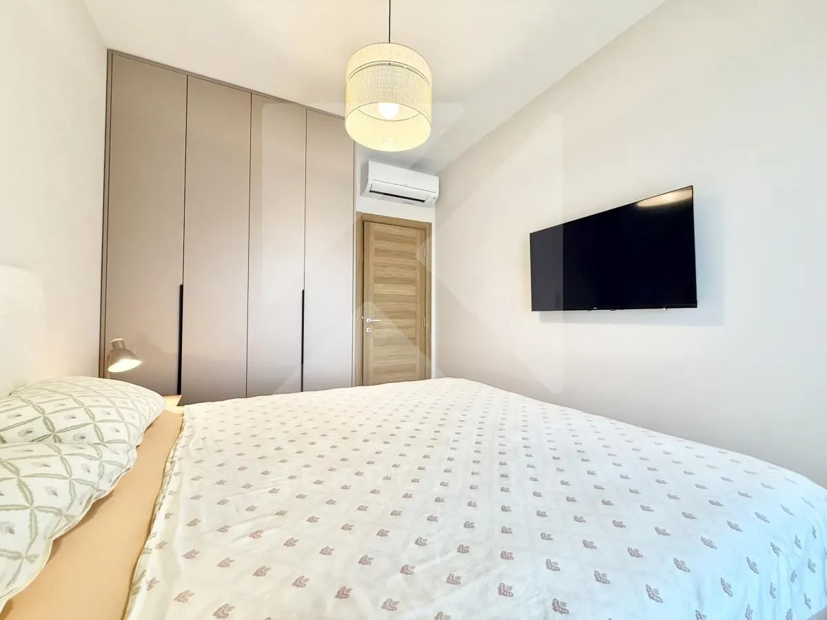 Modern bedroom with a double bed, built-in wardrobe, and a wall-mounted TV.