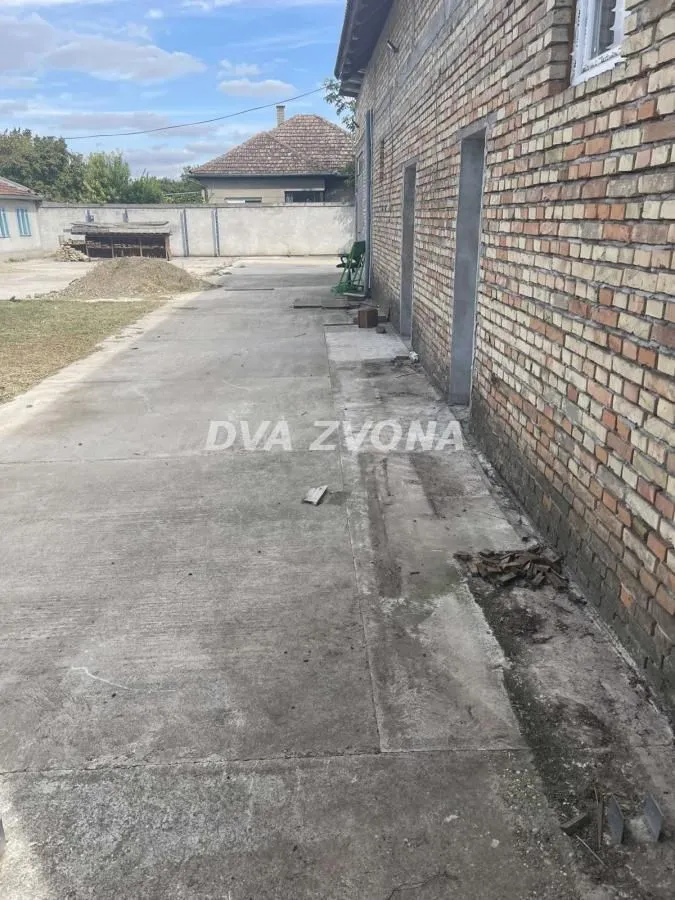 Betonsko dvorište pored kuće sa fasadom od cigle.