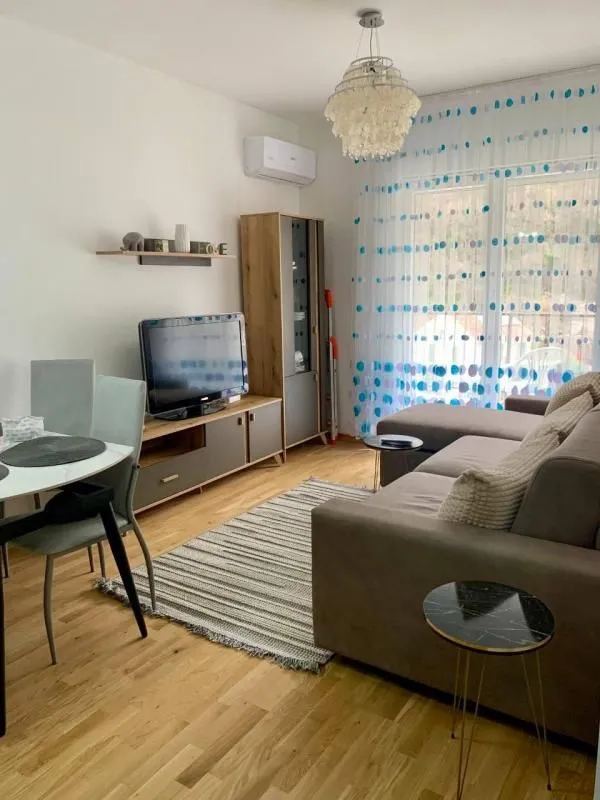 Living room with sofa, TV unit, and dining table.
