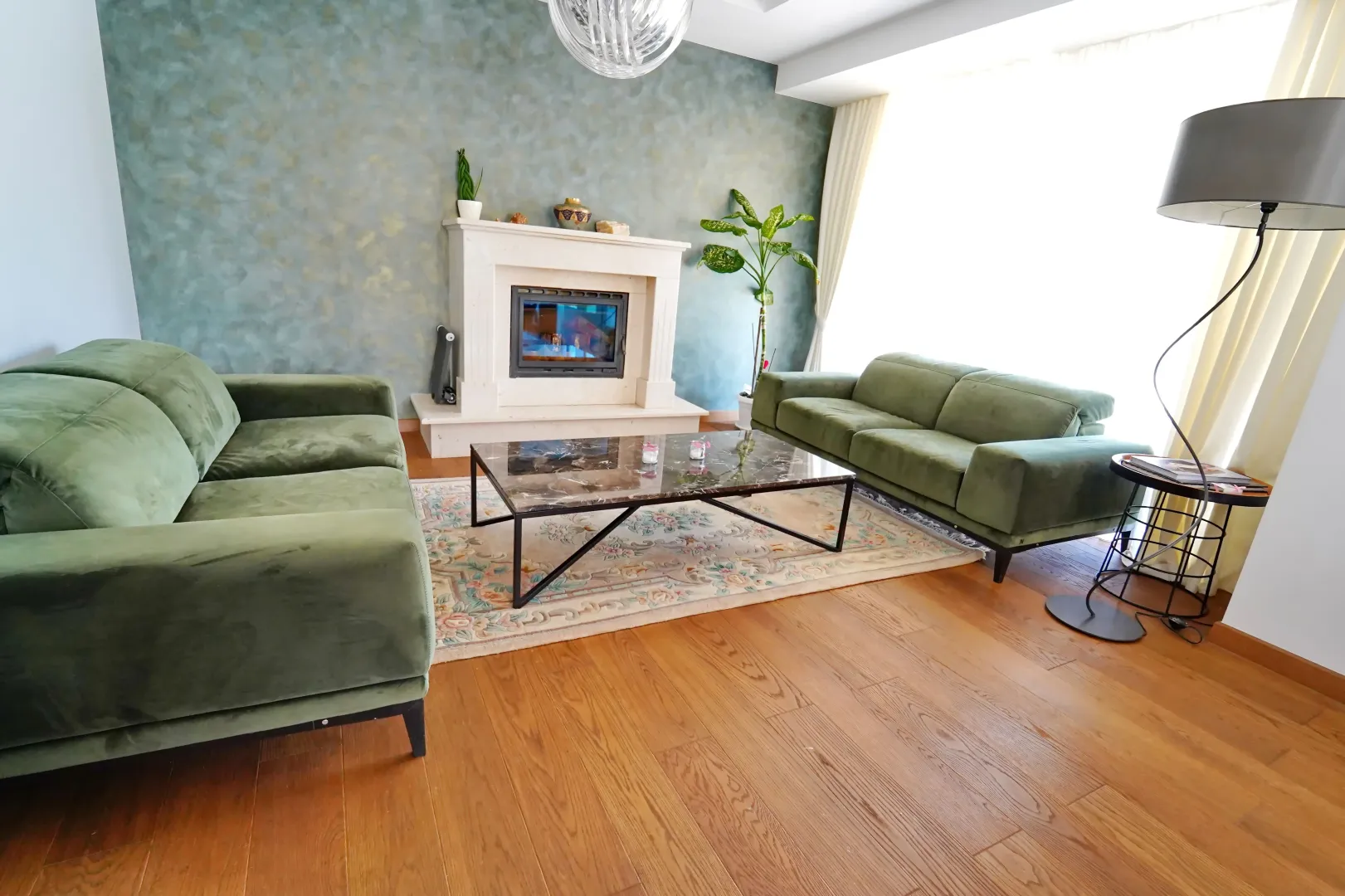 Spacious and bright living room with a fireplace and green sofas.