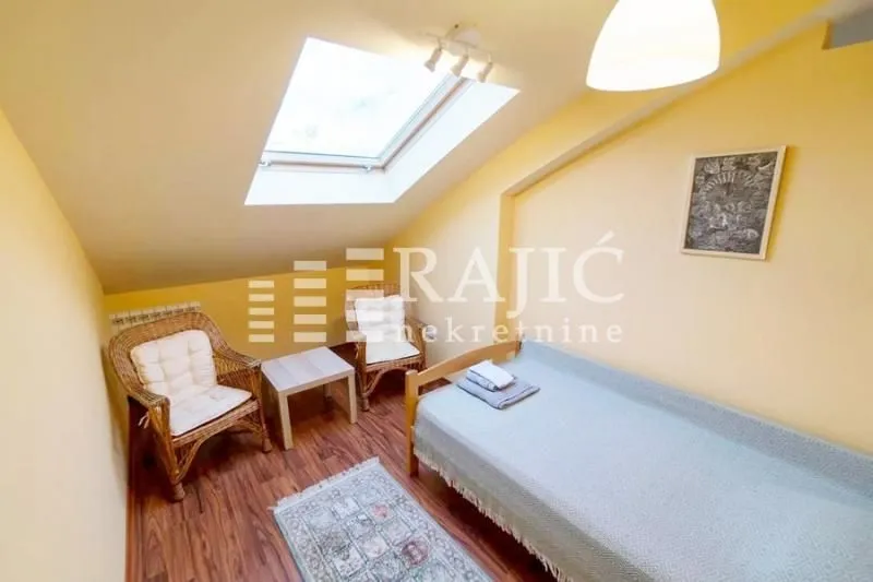 Attic bedroom with a single bed, skylight, and wicker armchairs.