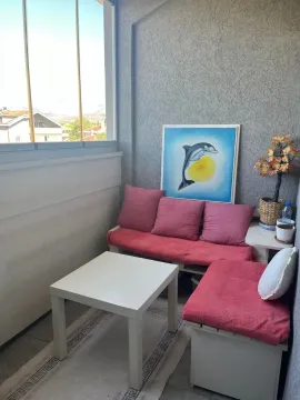 Glazed balcony with seating benches, cushions, and a small table. - image 5