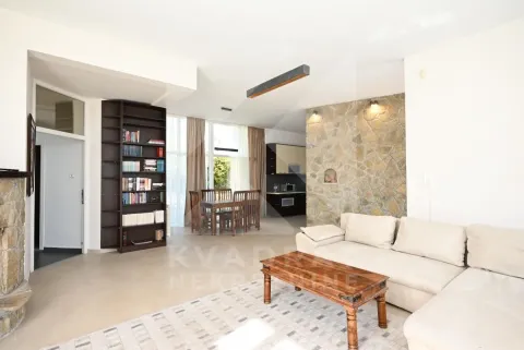 Living room with a sofa, bookshelf, and dining area in the background. - image 10