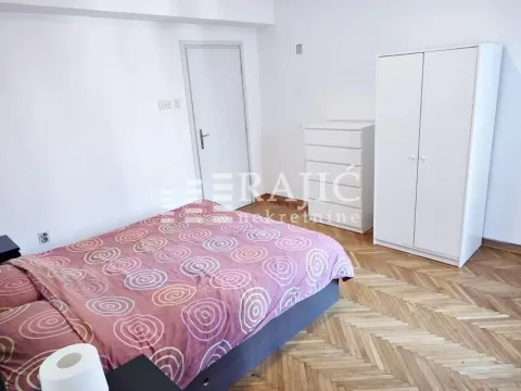 Furnished bedroom with a double bed, white wardrobe, and parquet flooring. - image 13