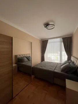 Moderna spavaća soba sa bračnim krevetom, garderoberom sa ogledalom i velikim prozorom. - image 2