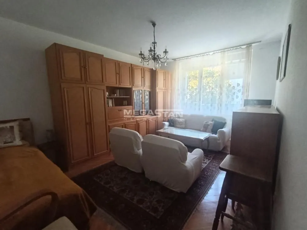 Living room with sofa set, large wooden wardrobe and window.