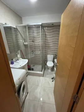 Small bathroom with a shower cabin, washbasin, toilet, and washing machine. - image 3