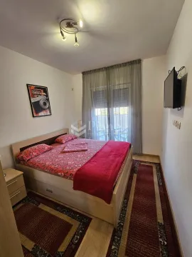 Spavaća soba sa bračnim krevetom, noćnim stočićem i televizorom na zidu. - image 5