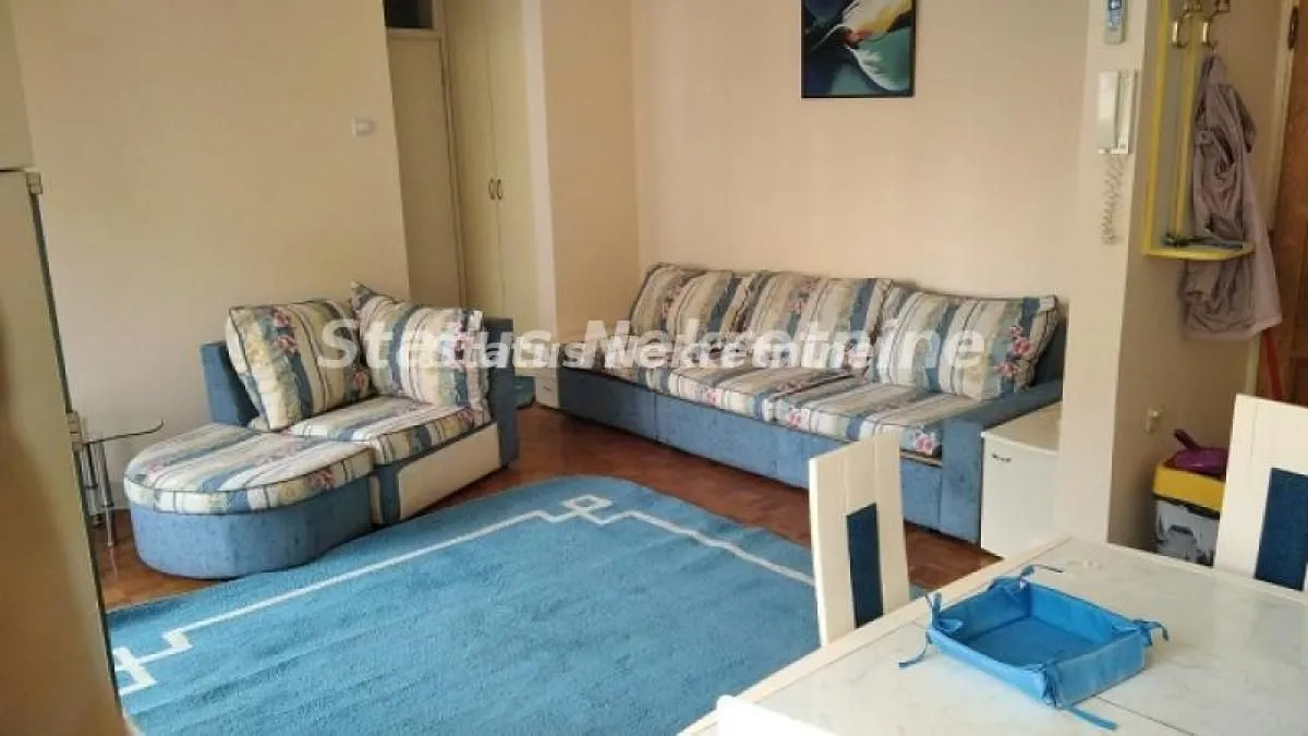 Dnevna soba sa garniturom za sedenje i trpezarijskim stolom.
