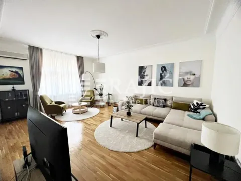 Spacious living room with a sofa, TV, and seating area. - image 16