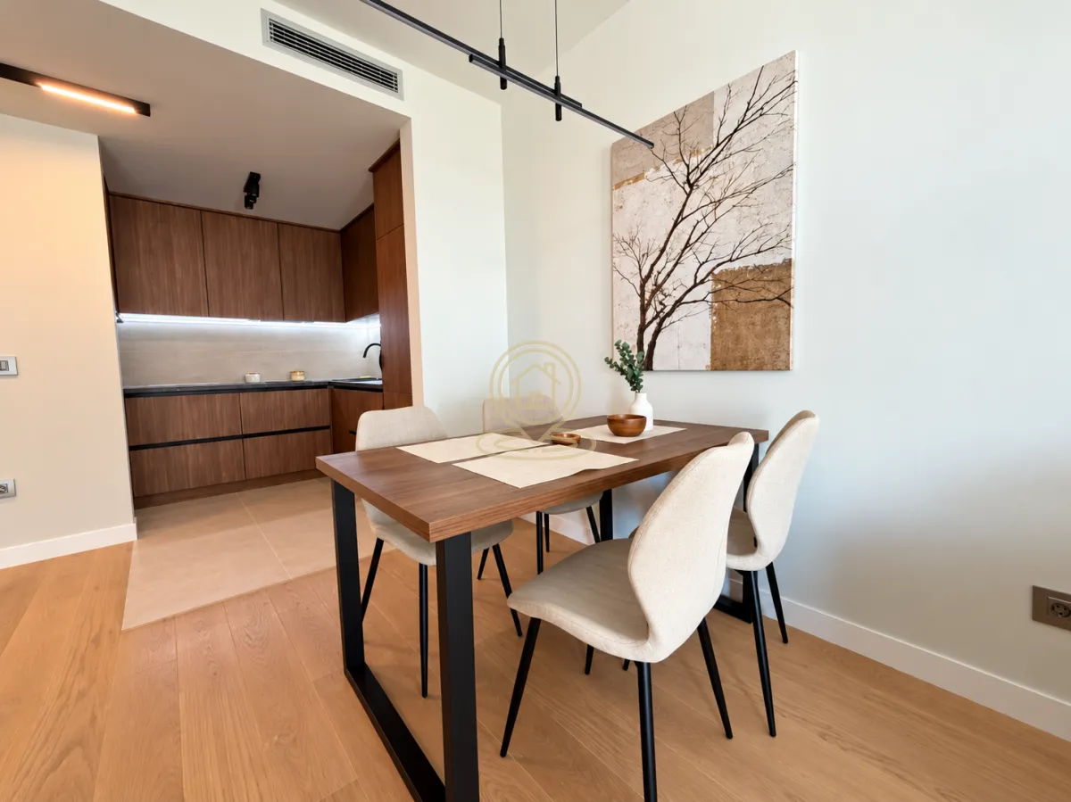 Dining area with a wooden table and chairs, overlooking the kitchen.