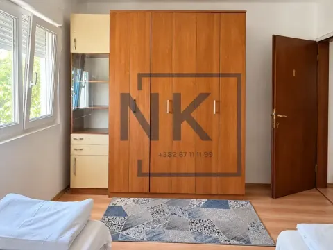 Namještena spavaća soba sa velikim drvenim ormarom i dva kreveta. - image 2