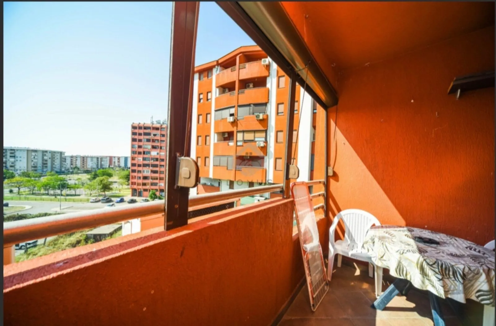 Covered balcony with seating furniture and a view of the neighborhood.