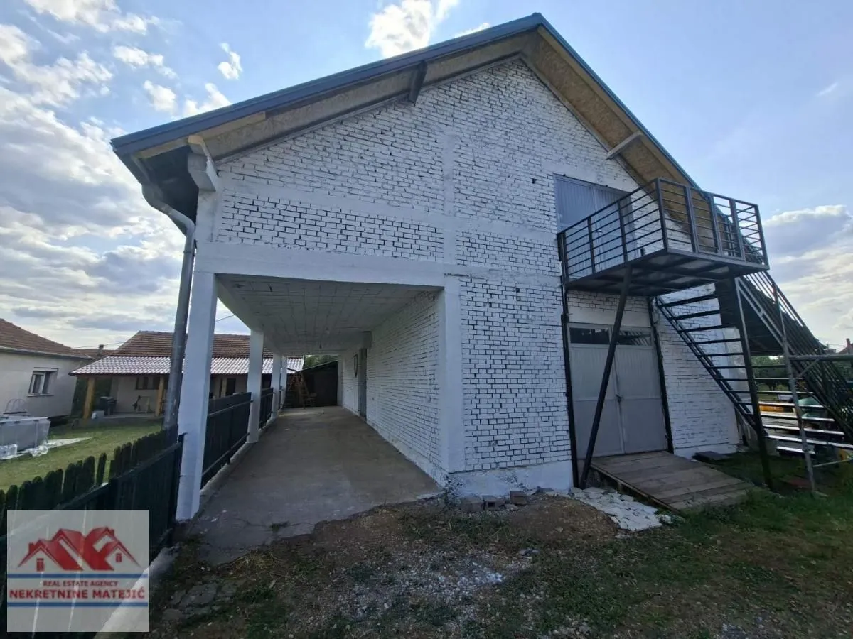 Exterior view of the house with a covered ground floor area and external staircase.