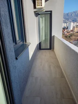 Small tiled balcony with a view of surrounding buildings and mountains. - image 5