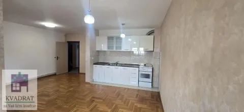 Manja kuhinja sa belim elementima i šporetom u sklopu prostorije sa parketom. - image 4