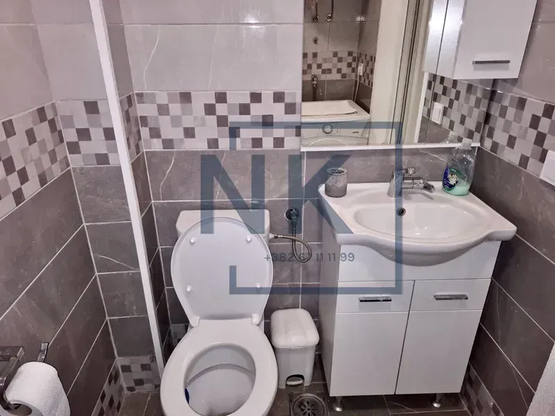 Manje kupatilo sa umivaonikom, ormarićem i toaletom.