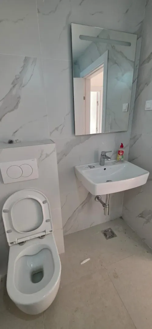 Moderno opremljeno kupatilo sa bijelim sanitarijama i mermernim pločicama.