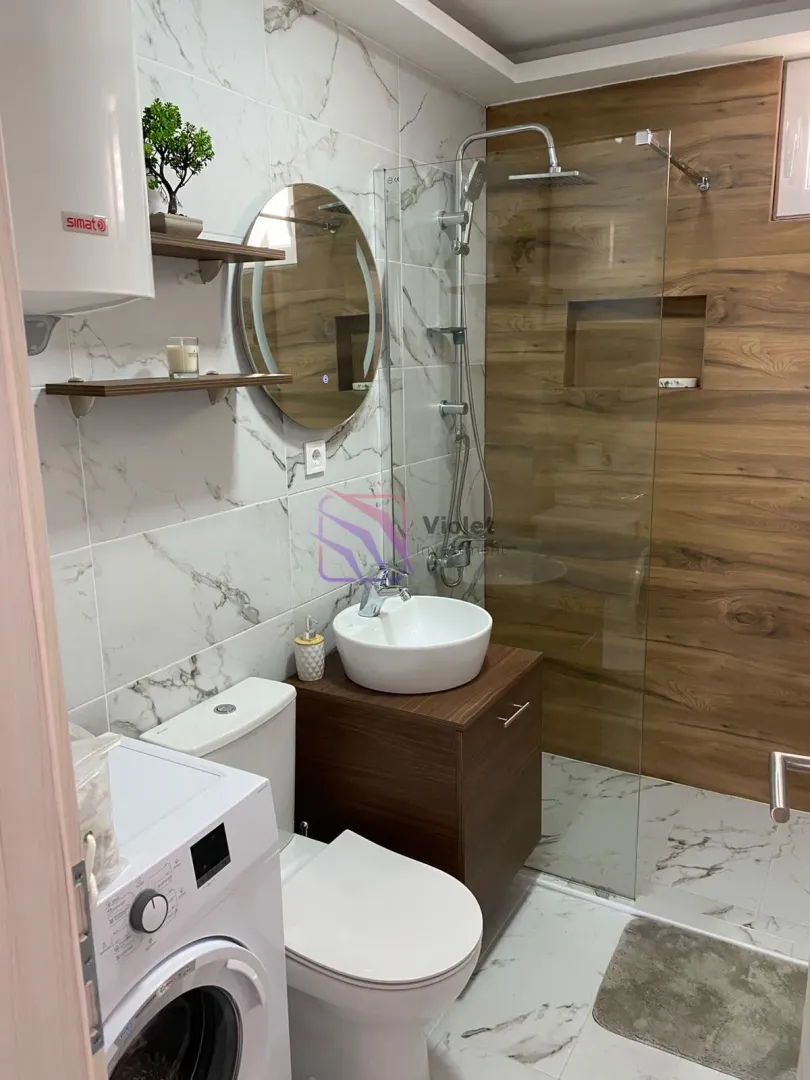 Modernly equipped bathroom with a shower cabin, washbasin and washing machine.