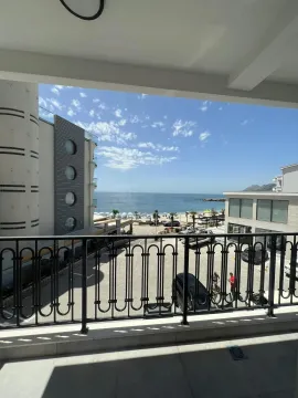 View from the balcony towards the sea and nearby buildings. - image 6