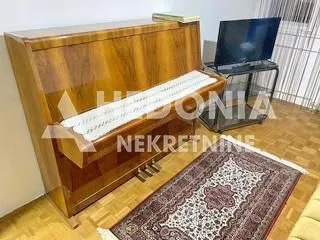Dnevna soba sa klavirom i televizorom.
