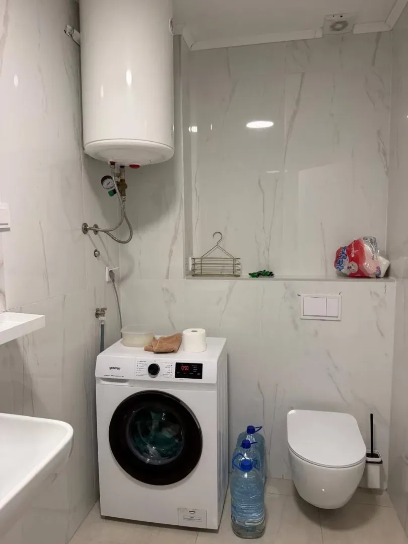 Modernly equipped bathroom with a washing machine and a water heater.