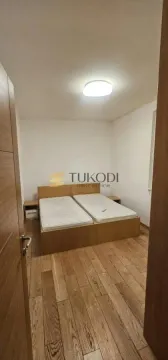Spavaća soba sa dva spojena kreveta i drvenim podom. - image 5