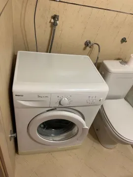 Bathroom equipped with a toilet and washing machine. - image 9