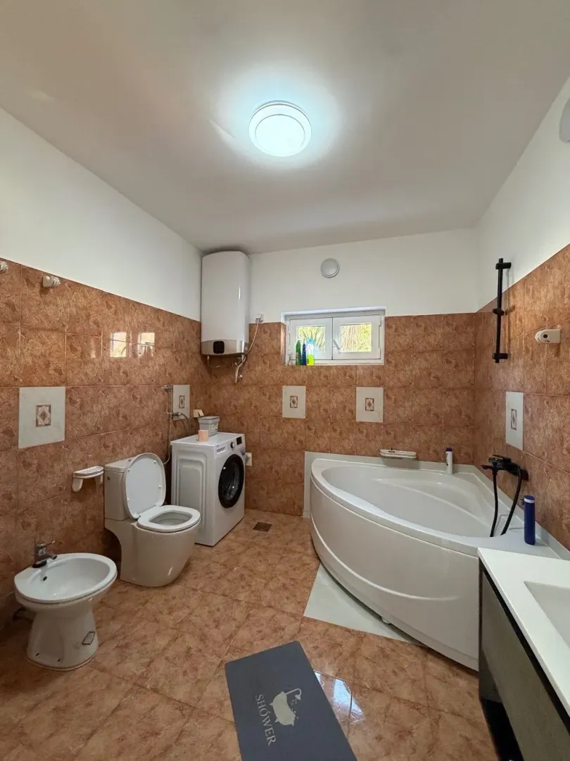 Kupatilo opremljeno kadom, sanitarijama i veš mašinom.