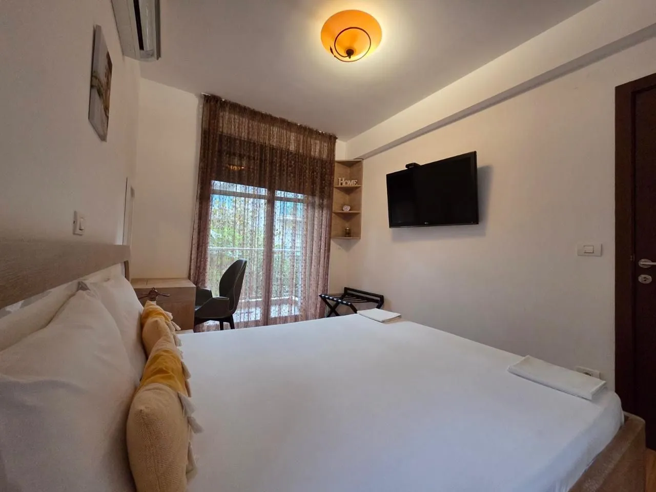 Furnished bedroom with a large double bed and a wall-mounted TV.