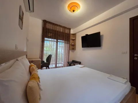 Furnished bedroom with a large double bed and a wall-mounted TV. - image 13