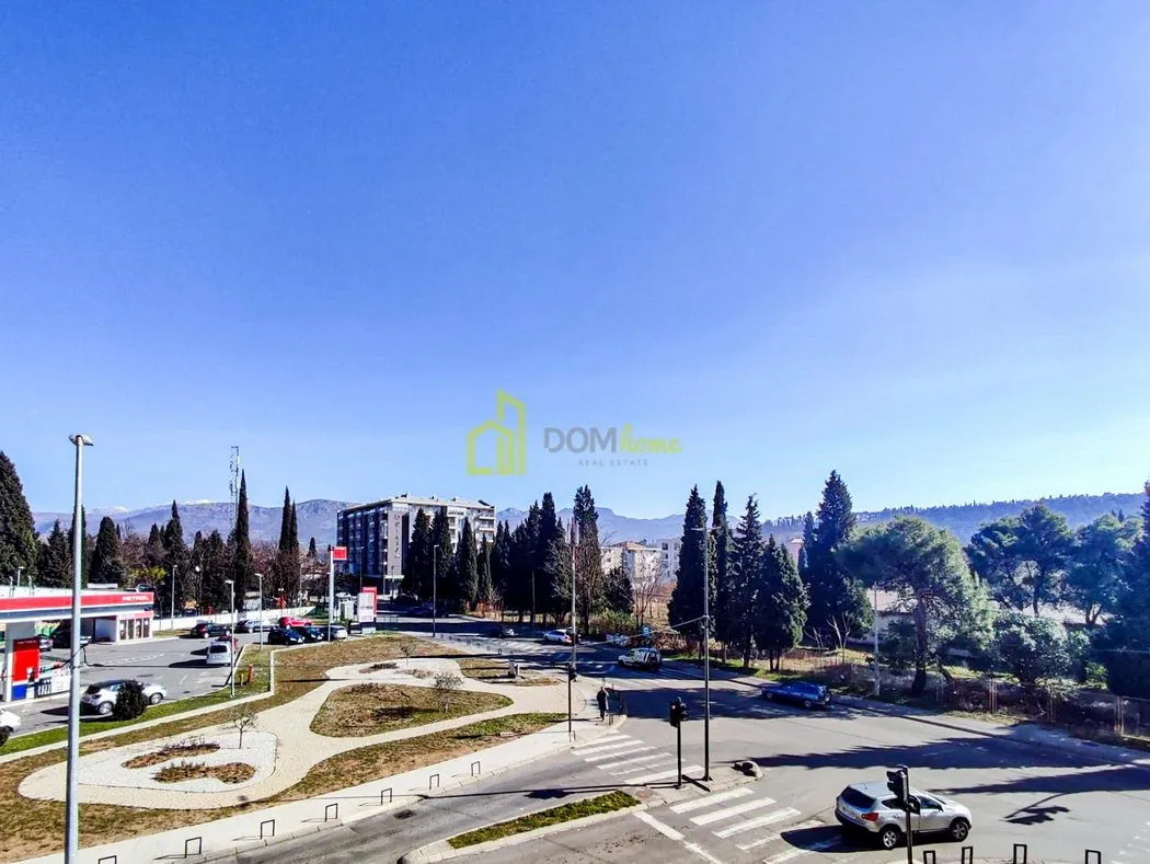View from the window showing surrounding streets, greenery, and mountains in the background.
